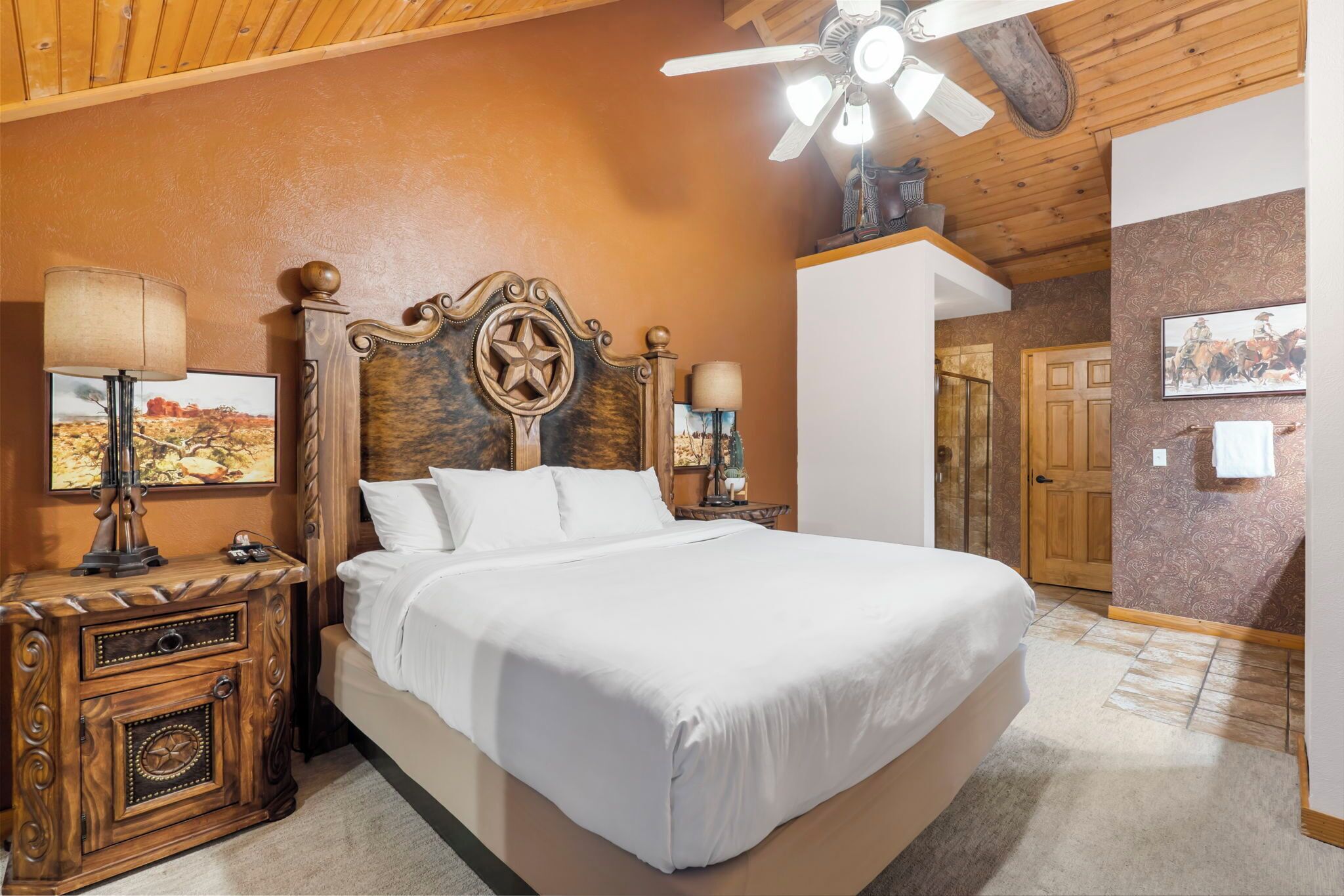 A bedroom with a large bed, wooden headboard, two bedside tables with lamps, and a ceiling fan.