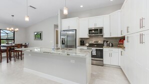 A modern kitchen with white cabinets, stainless steel appliances, and a large island.