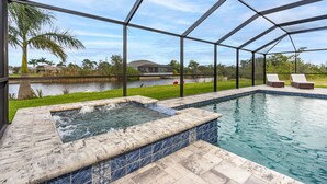 A swimming pool with a hot tub, surrounded by a covered patio with lounge chairs.
