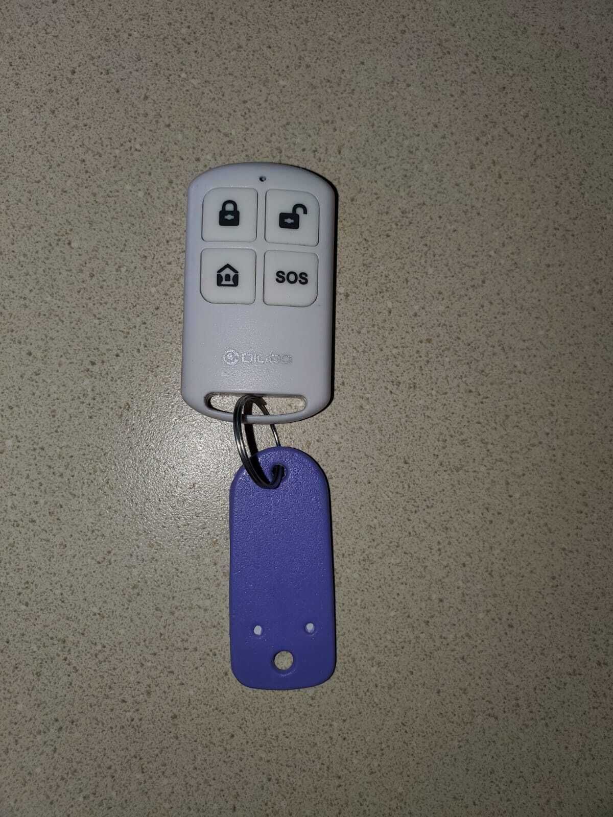 A key fob with a house icon, lock icon, and SOS button, attached to a blue tag.