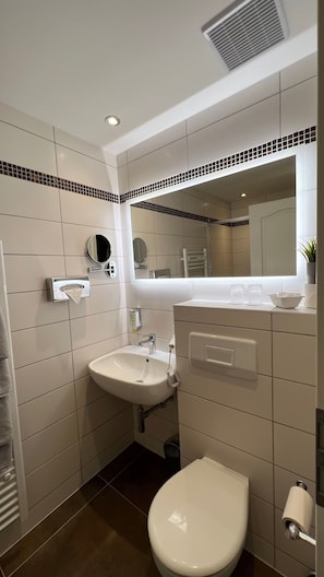Une salle de bain moderne avec un lavabo blanc, un miroir et des toilettes.