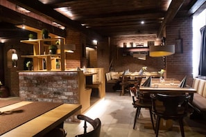 Un restaurant chaleureux avec des murs en briques, des meubles en bois et des luminaires suspendus.