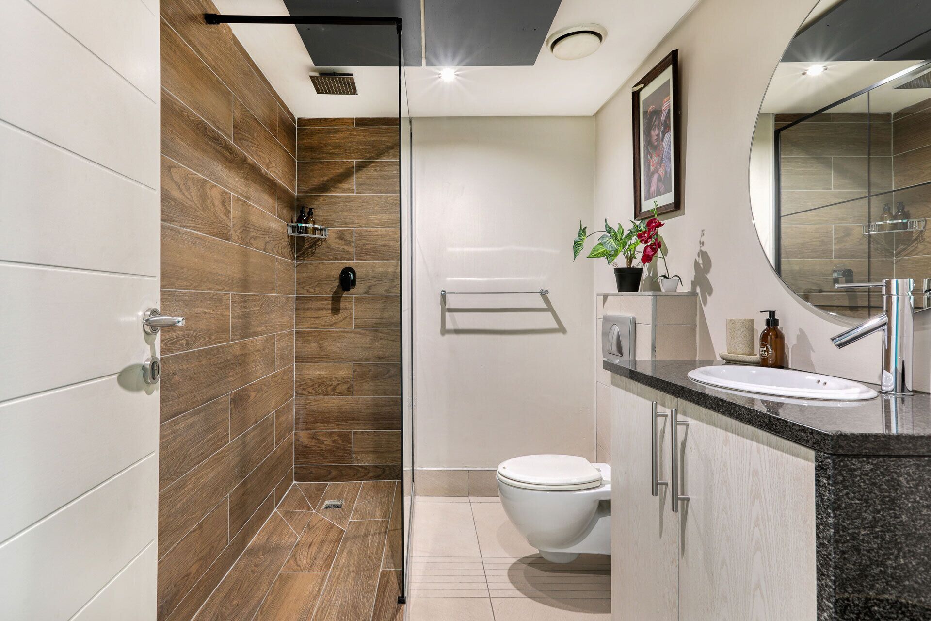 A modern bathroom with a shower, toilet, and sink.