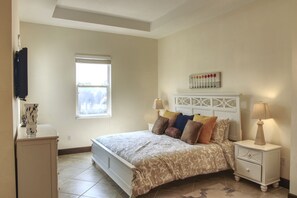 A bedroom with a bed, nightstands, a window, and a wall-mounted TV.