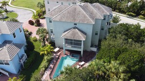 A multi-story building with a swimming pool, surrounded by lush greenery and palm trees. - Luxury Gulf Beach Living - Coronas Gris (Siesta Key)