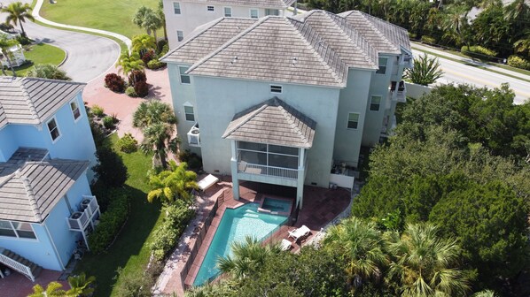 A multi-story building with a swimming pool, surrounded by lush greenery and palm trees.