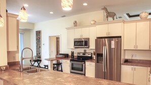 A modern kitchen with stainless steel appliances, a granite countertop, and pendant lighting. - Luxury Gulf Beach Living - Coronas Gris (Siesta Key)
