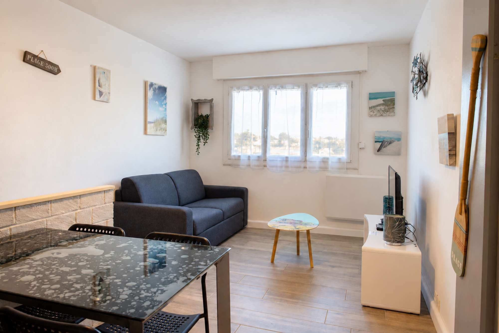 A compact living space with a sofa, a small table, a decorative item, and a window with curtains.