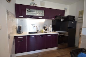 A kitchen with dark cabinets, a black refrigerator, a microwave, and a stove.