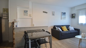 A modern living space with a dining area, a sofa, and a small table.