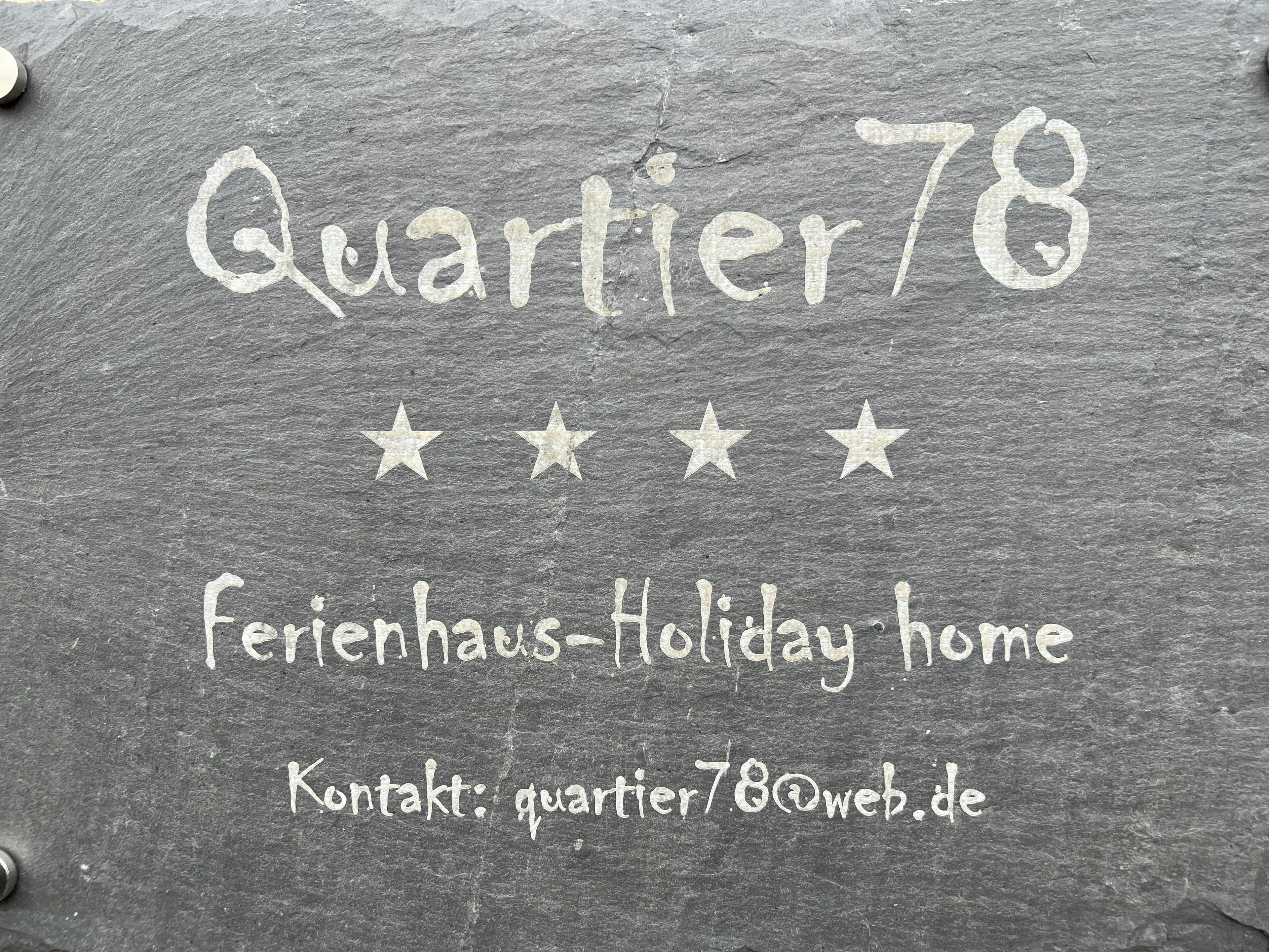 Eine Kreidetafel mit der Aufschrift 'Quartier78' und 'Ferienhaus', sowie einer Kontakt-E-Mail-Adresse.