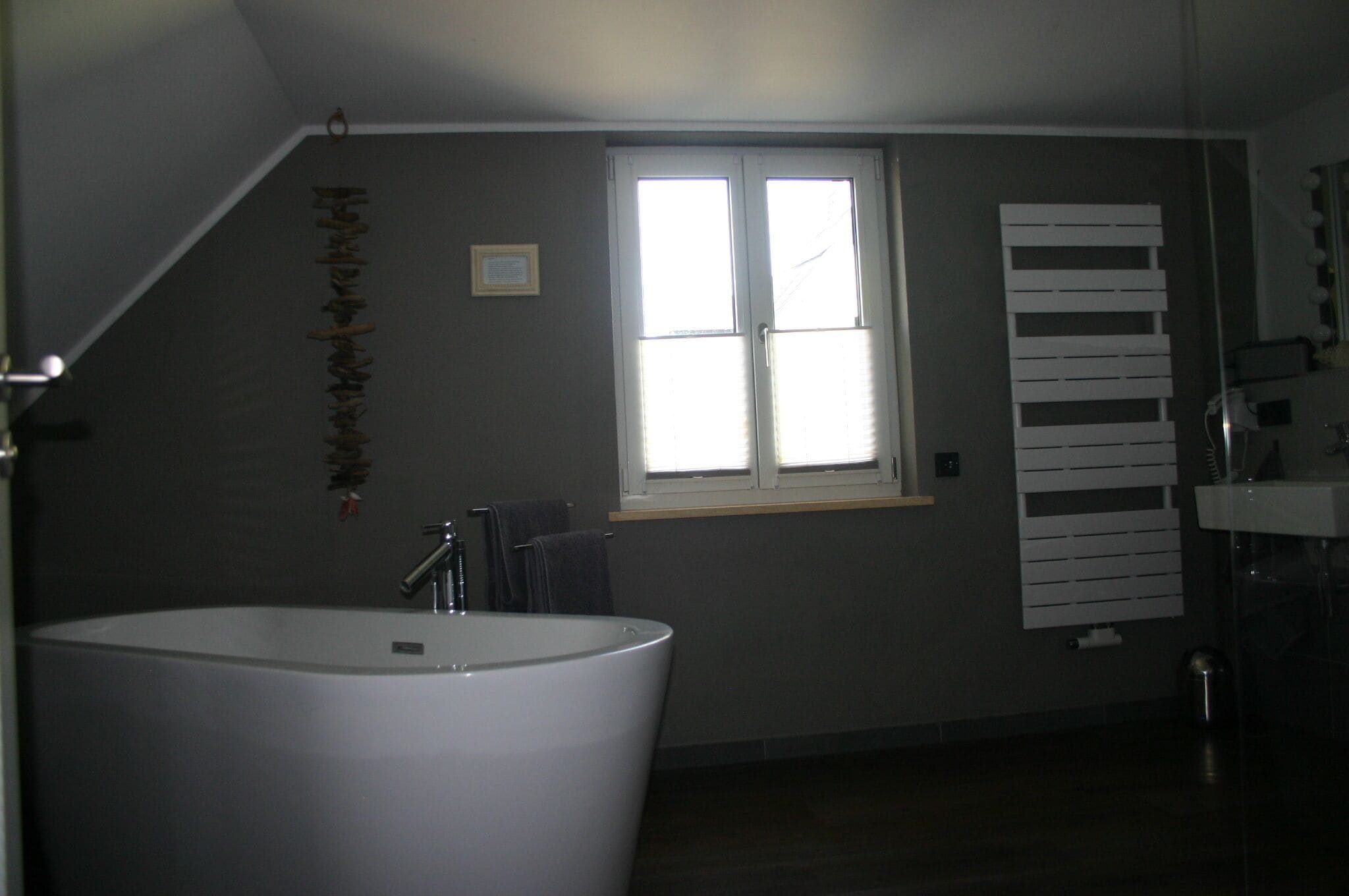 Ein Badezimmer mit Badewanne, Fenster und Handtuchhalter.