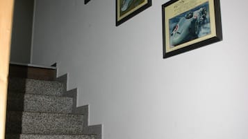 A staircase with granite steps leading to a landing where four framed pictures are hung on the wall.