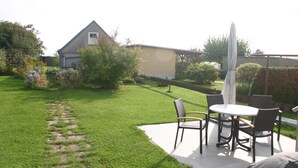 A patio with a table and chairs, a covered umbrella, and a lawn with a path. - Quartier78 - Welcome to friends in Mittweida  (Mittweida)