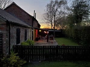 A brick building with a tiled roof, a wooden fence, and a grassy yard. - 2-bed 18th Century Barn - Sleeps 6 - Pet Friendly (Boston)