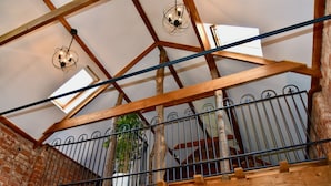 Un balcon en bois avec des balustrades en métal, un mur en briques et un luminaire suspendu.
