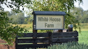 Une enseigne en bois portant l’inscription « White House Farm », située dans un cadre rural.