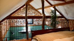 Une chambre avec vue sur une piscine, un plafond en bois et un mur en briques.