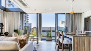 A modern apartment with a living room, dining area, and balcony. - Always-Power Stunning Apartment with 180 Degree City View near V&A Waterfront (Cape Town)