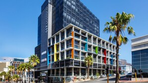 A multi-story hotel with a modern design, featuring a mix of glass and concrete facades, and a prominent vertical stripe pattern. - Always-Power Stunning Apartment with 180 Degree City View near V&A Waterfront (Cape Town)
