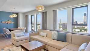 A modern living room with a sectional sofa, a dining table with chairs, and large windows offering a city view. - Element by Marriott Al Jaddaf, Dubai (Dubai)