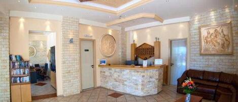 Un hall con mostrador de recepción, un sofá de cuero marrón, una mesa de centro y una estantería.