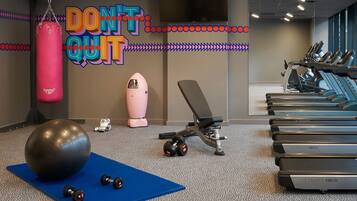 A gym with exercise equipment, a punching bag, and a motivational wall sign.