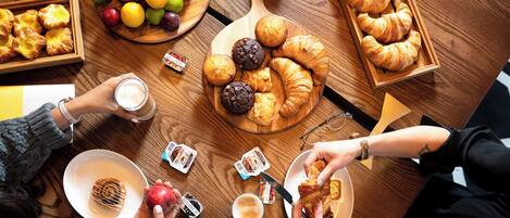 A wooden table with various food items, including pastries, fruits, and condiments.