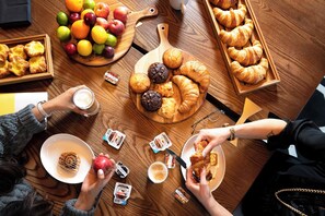 A wooden table with various food items, including pastries, fruits, and condiments.