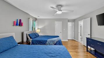 A bedroom with two beds, a ceiling fan, and a dresser.