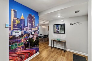 Un intérieur moderne agrémenté d’une fresque représentant un paysage urbain, d’une table de conférence et d’un tableau encadré au mur.