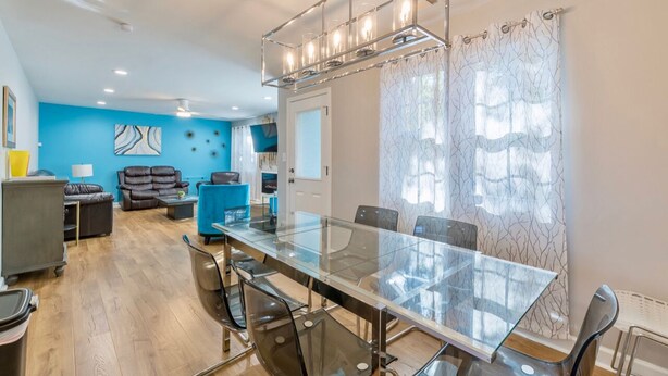 A modern living room with a glass dining table, leather sofas, and a blue accent wall.