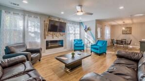 A modern living room with leather sofas, a flat-screen TV, and a fireplace.