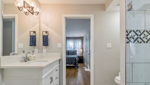 A modern bathroom with a large mirror, a vanity with a sink, and a shower area.