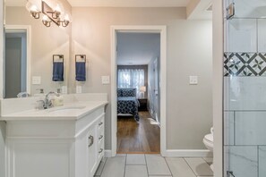 A modern bathroom with a large mirror, a vanity with a sink, and a shower area. - Close to Downtown, Modern 3 BR w/Driveway (Atlanta)