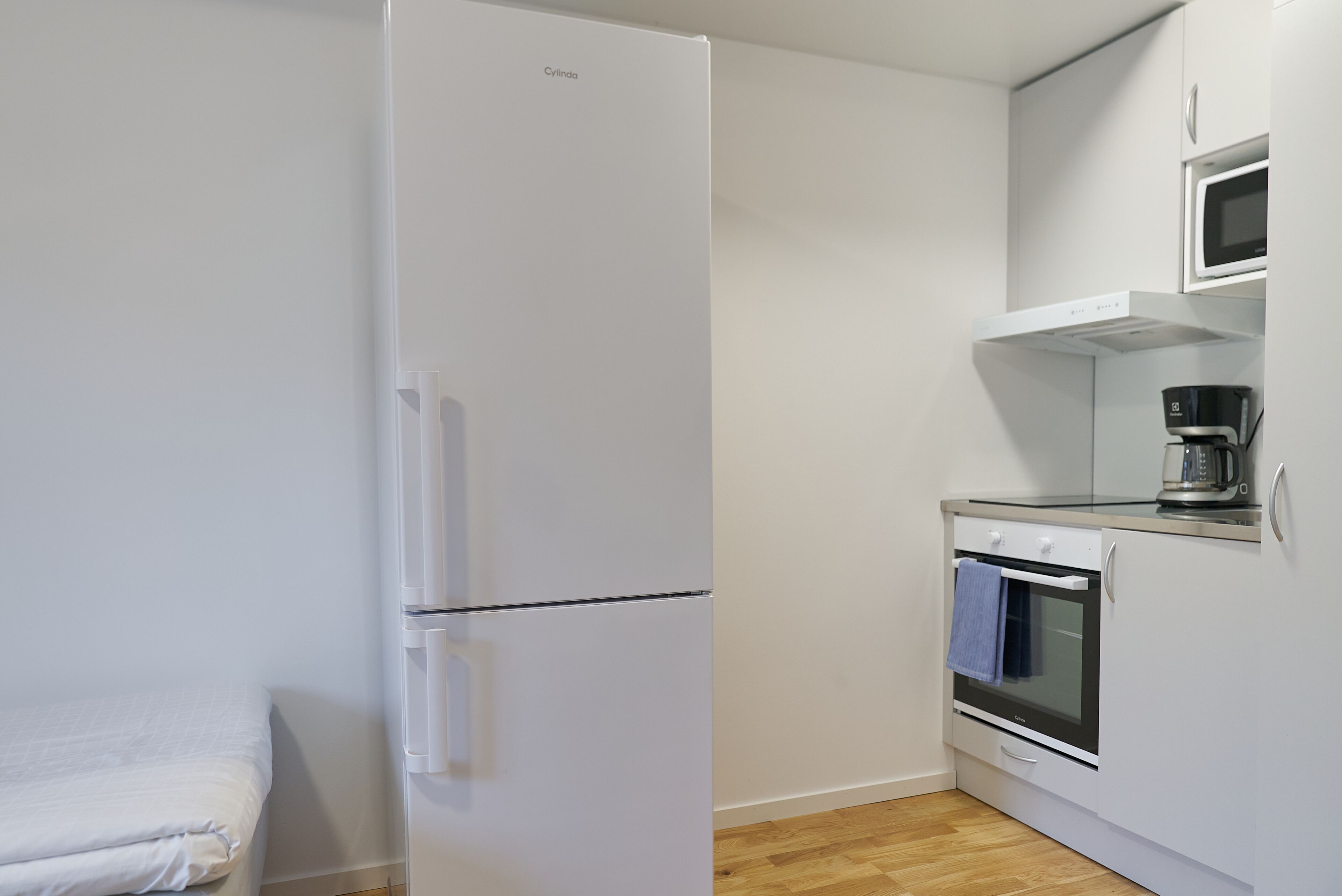 A compact kitchen with a white refrigerator, a microwave, and a coffee maker on the countertop.