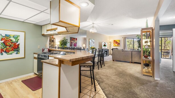 Una cocina moderna con una isla central, un comedor con sillas y una sala de estar con sofá.