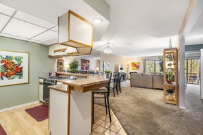 Une cuisine moderne dotée d’un îlot central, un coin repas avec des chaises et un salon avec un canapé.