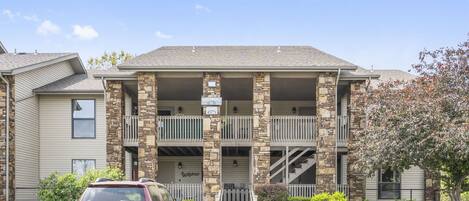 A two-story building with a stone facade and a parking lot in front.