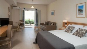A hotel room with a bed, a desk, a chair, a TV, a sofa, and a balcony with a view. - Estia Hotel (Pylos-Nestoras)