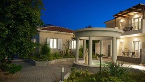 A two-story building with a circular patio, stone walls, and a small fountain. - Estia Hotel (Pylos-Nestoras)