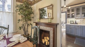 A dining area with a fireplace, a mirror, and a plant. - 3812 Little House - Historic Home, Walk to the Bay (Pacific Grove)