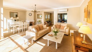 A spacious living room with a sofa set, a coffee table, and a dining area with chairs and a table. - Vila Sol: Nice apartment with large south-facing terrace and view of own park (Quarteira)
