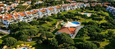 A resort with multiple buildings, a swimming pool, and well-maintained lawns.