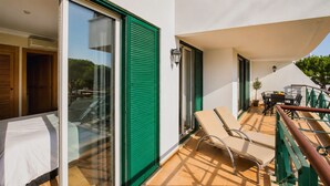 A balcony with a table and chairs, a potted plant, and a sliding glass door. - Vila Sol: Nice apartment with large south-facing terrace and view of own park (Quarteira)