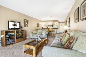 A living room with a sofa, coffee table, and entertainment unit. There is a television on the entertainment unit. - 2 King, 2 Bath Golf Condo with Private Deck. Ticket Deals (Branson)