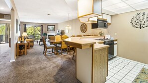 Una cocina moderna con una isla central, una zona de comedor con sillas y vistas al exterior.