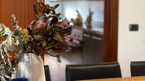 Ein Esstisch mit einer Vase getrockneter Blumen und einer blauen Schüssel.