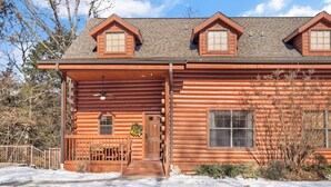 A log cabin with a front porch, a staircase leading to the main entrance, and a number '207' on the door.