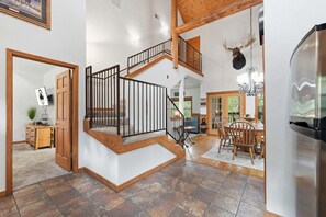 Un intérieur spacieux avec un escalier en bois, un coin repas et une cuisine.